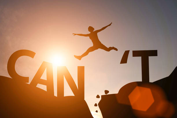Silhouette man jump between can't wording and can wording on mountain. Mindset for career growth business. Silhouette man jump between can't wording and can wording on mountain. Mindset for career growth business. overcome adversity stock pictures, royalty-free photos & images