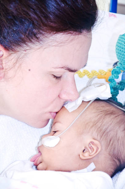 mère embrassant l'enfant récupérant après chirurgie ouverte de coeur - family mouth open vertical mother photos et images de collection