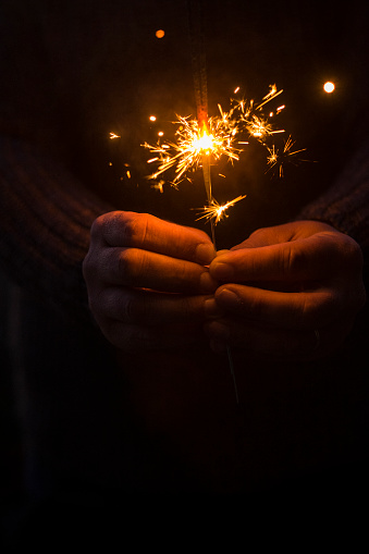 Concept of party nightlife and new year eve 2020 - close up of people hands with red fire sparklers to celebrate the night and the new start - warm colors filter