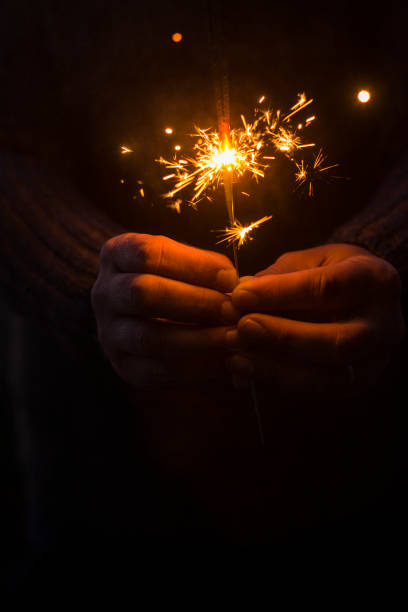 Concept of party nightlife and new year eve 2020 - close up of people hands with red fire sparklers to celebrate the night and the new start - warm colors filter stock photo