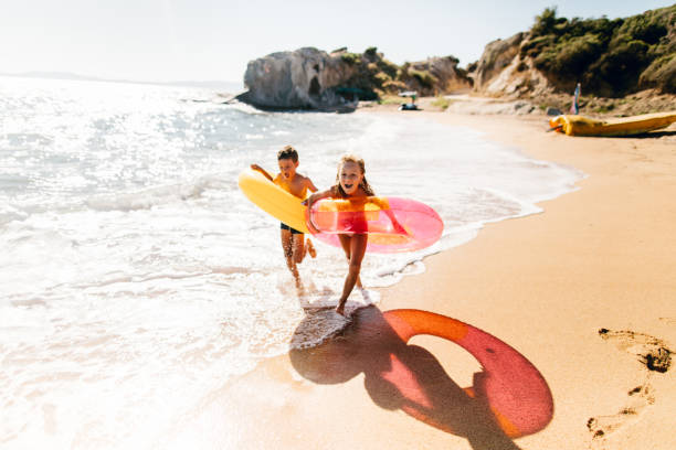 hermano y hermana disfrutando de la mañana de verano en la playa - family beach vacations travel fotografías e imágenes de stock