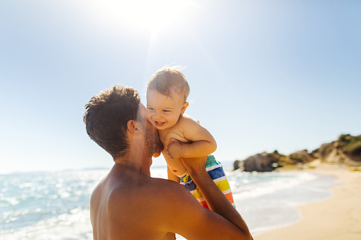 Photo of smiling baby boy with his daddy at the beach