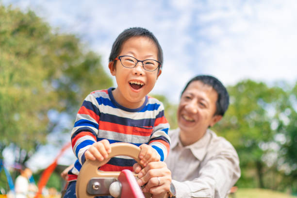 istock Child with down syndrome enjoying with his father at public park 1183777314