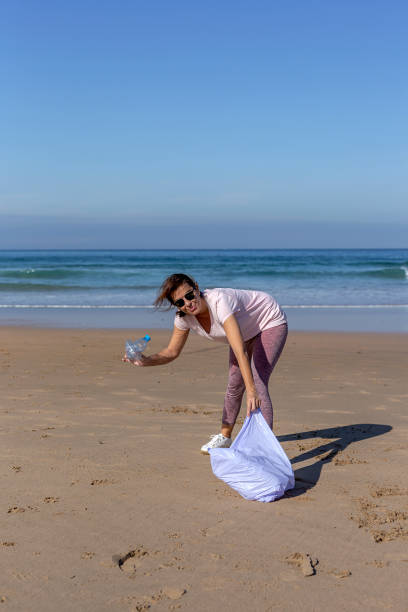 istock Woman picking up trash and plastics cleaning the beach 1183779006