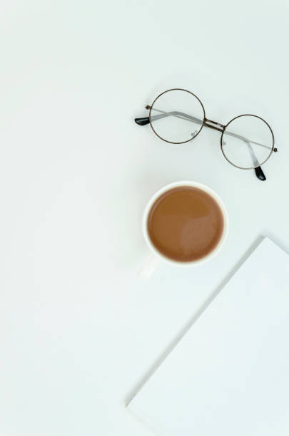 istock Top view desktop with coffee cup, glasses and blank magazine with copy space. Vertical shot 1183783263