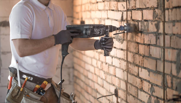 istock Handyman uses jackhammer, for installation, professional worker on the construction site. The concept of electrician and handyman. 1183783606
