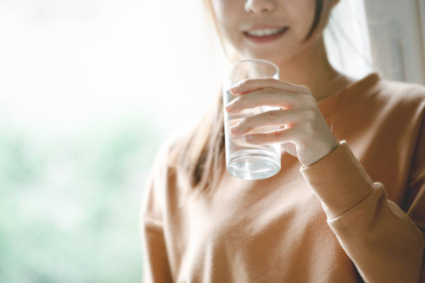 donna felice che beve acqua mentre sorride. - house home interior water glass foto e immagini stock
