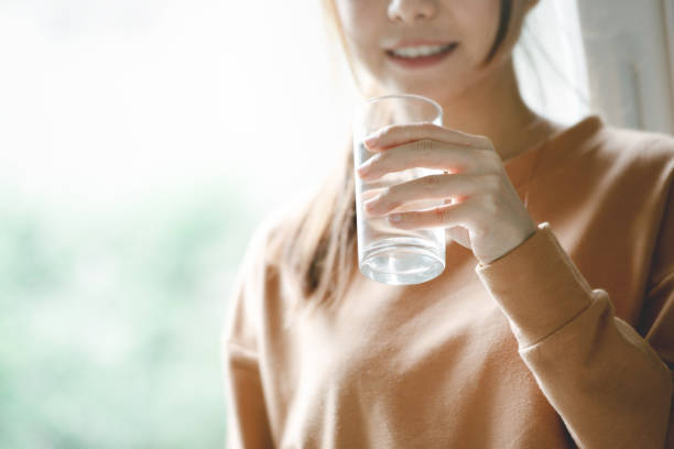 happy woman drinking water while smiling. - water human hand people women imagens e fotografias de stock