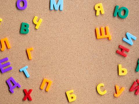 Frame from colorful Cyrillic plastic magnetic letters on cork desk. Learning languages concept.