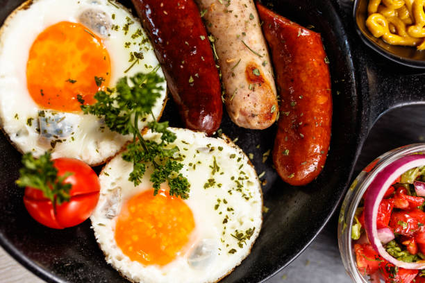 istock Fried eggs sunny side up served with sausage in a cooking pan 1183785228