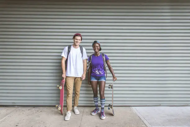 Young adults skating outdoors - Stylish skater boy and girl training in a New York skate park, concepts about sport and ifestyle