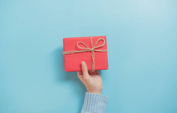 istock Woman Hands holding craft paper gift box on blue background and copy space. for present Christmas, new year, valentine day or anniversary. 1183788884