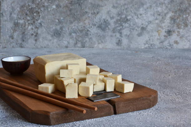 istock Soy cheese - classic tofu cheese on a wooden board on the kitchen table. 1183789078