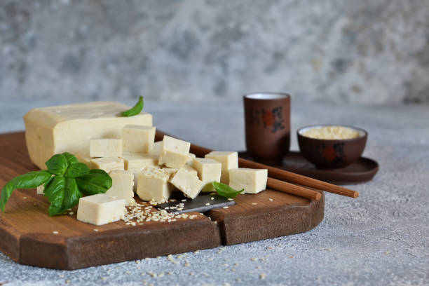 istock Soy cheese - classic tofu cheese on a wooden board on the kitchen table. 1183789086
