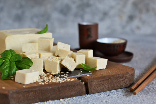 istock Soy cheese - classic tofu cheese on a wooden board on the kitchen table. 1183789103