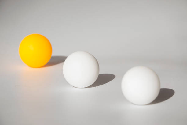 istock Yellow and white ping pong balls on a white background with hard light and shadows 1183790078