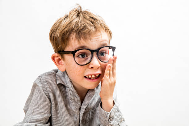 smiling toothless boy touching his oversized eyeglasses for symbol of cute fun genius child thinking, isolated portrait over white background