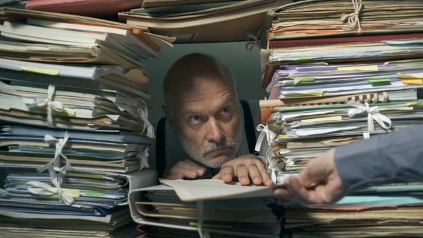 istock Creepy office clerk overloaded with paperwork 1183795588