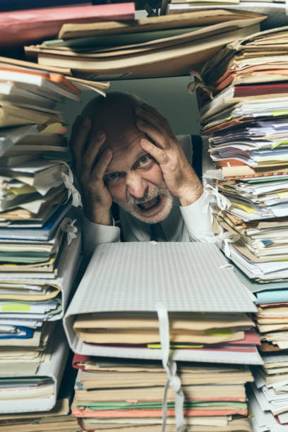 istock Panicked businessman overwhelmed with paperwork 1183795770