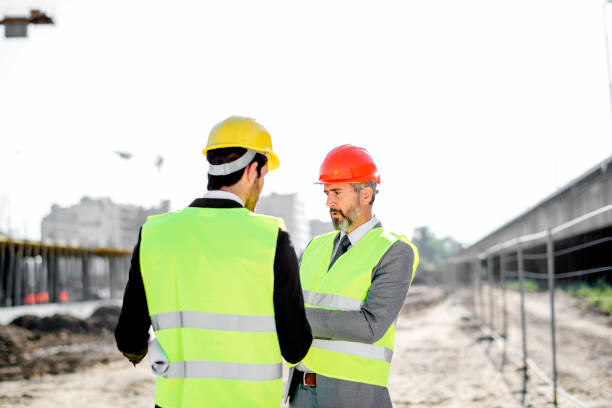 istock Young and senior engineer holding blueprint and tablet on construction site 1183797150