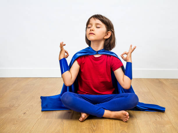 orgoglioso bambino supereroe pratica yoga e meditazione per l'umorismo zen - spirituality yoga zen like meditating foto e immagini stock