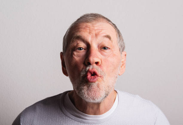 Portrait of a cheerful senior man in a studio, making funny faces.