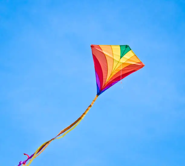 A beautiful, colourful stunt kite, in the blue sky, high up in the wind