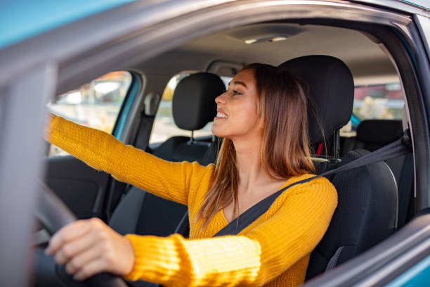istock Happy young woman driver looking adjusting rear view car mirror 1183801724