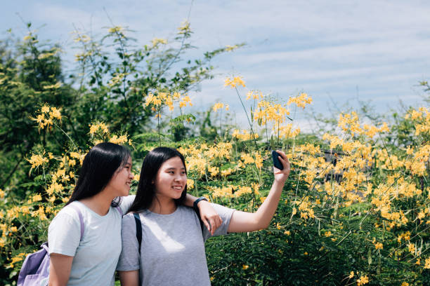 istock Asian Twin Sisters Taking Selfie Photos While Travelling Outdoors Together 1183802397