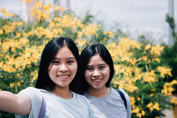 Asian Twin Sisters Taking Selfie Photos While Travelling Outdoors Together
