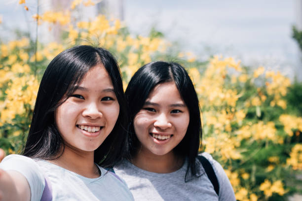 istock Asian Twin Sisters Taking Selfie Photos While Travelling Outdoors Together 1183802411
