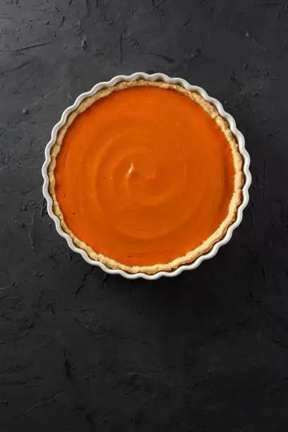Minimalist dessert. Homemade pumpkin pie on black background top view copy space