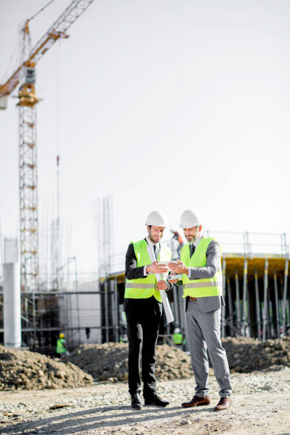 istock Young and senior engineer holding blueprint and tablet on construction site 1183806259
