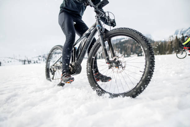 istock Midsection of mountain biker riding in snow outdoors in winter. 1183806359