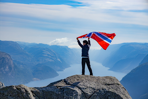 Woman with a waving flag of Norway on the background of nature