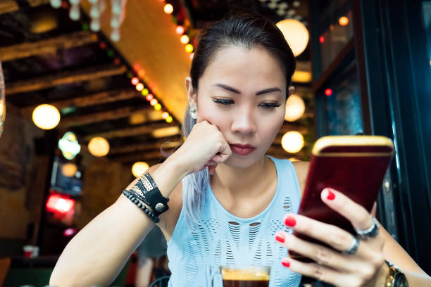 asian woman having bad news on mobile phone - escape from it all fotos imagens e fotografias de stock