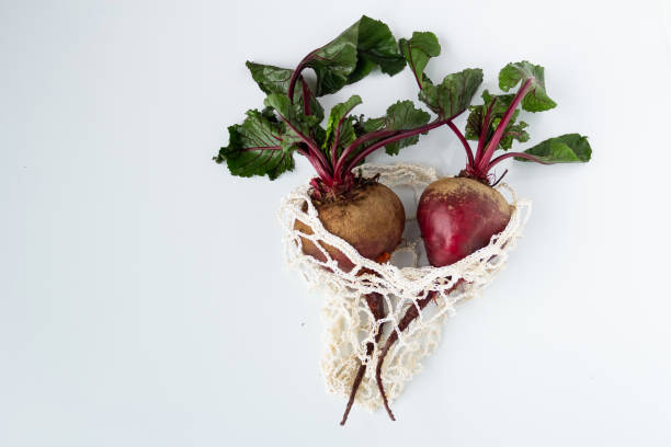 Two Fresh raw beets with tops in an eco bag close-up on a white background