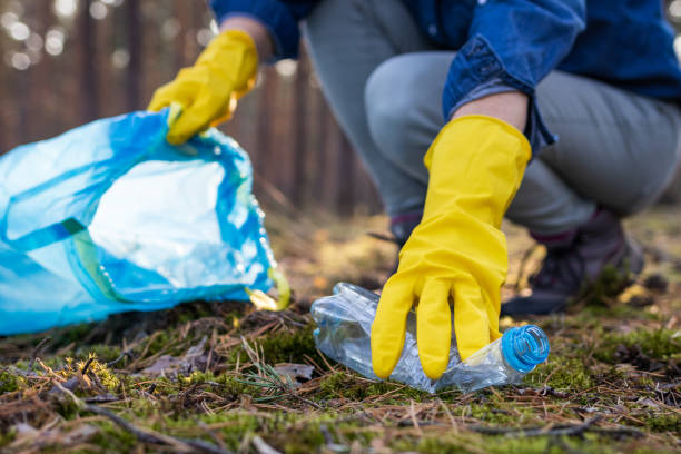 istock Environmental pollution. Volunteer picking plastic bottle in dirty forest. 1183812095