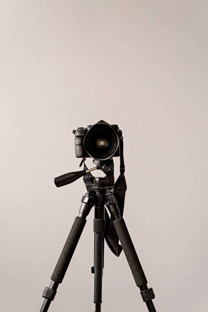 Photography concept. Professional camera on the black tripod isolated on gray background with copy space