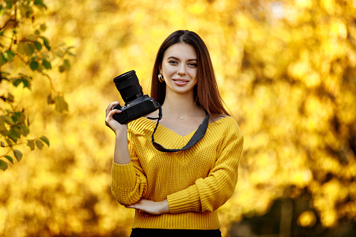 smiling woman photographer takes pictures in park. photographer with digital camera.