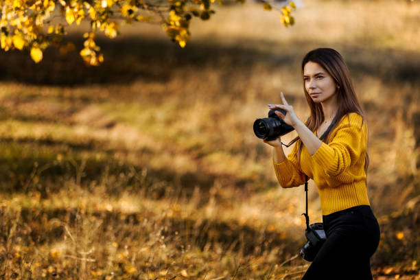 woman photographer takes pictures outdoor in autumn. space for text