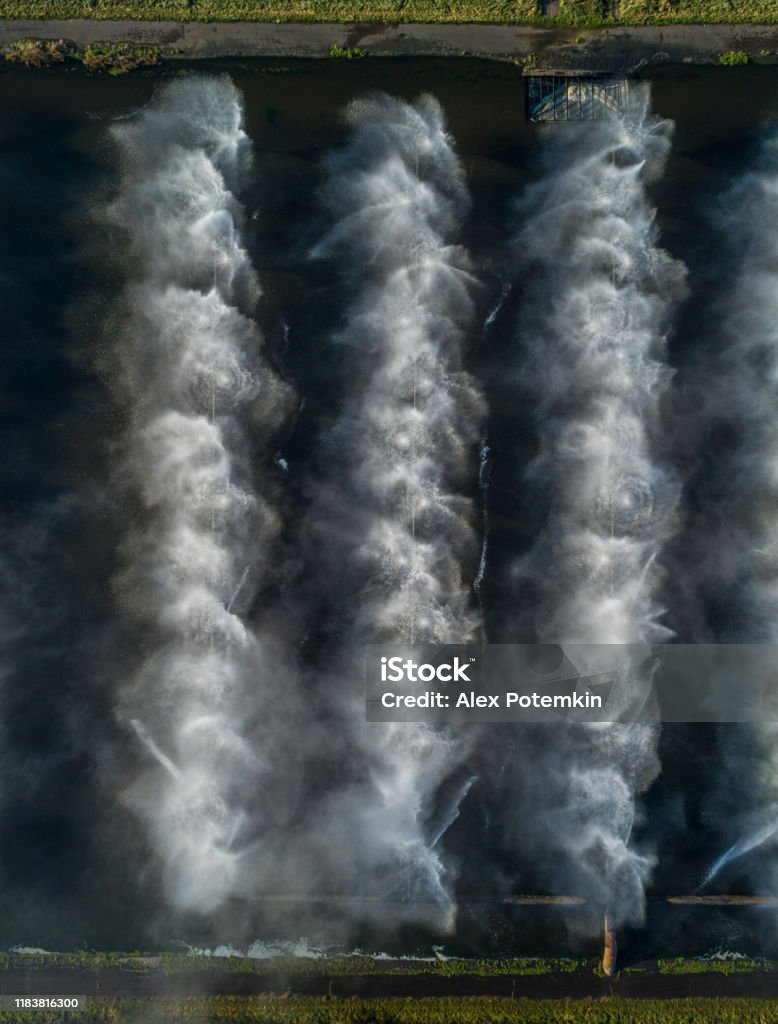 Looking-down directly above aerial drone view of industrial fountains on cooling basins of the thermal power plant. Industrial cooling fountains on the power plant. Belarus, Eastern Europe. Directly Above Stock Photo