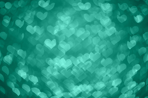 DSLR photo - defocused bokeh with a heart shape on an aquamarine background. Space for copy. Can be used as a Christmas background or other holiday background. It's a REAL bokeh photo, not an illustration or computer filter.