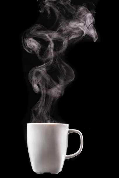 A white mug of warm drink and steam. Tasty hot coffee on a dark table. Black background. A white mug of warm drink and steam. Tasty hot coffee on a dark table. Black background. hot drink stock pictures, royalty-free photos & images