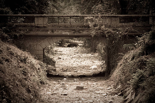 Empty river, dry river bed under stone bridge in drought