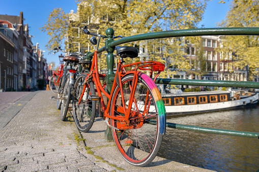 Orange bicycle with LGBT flag parked on a bridge in Amsterdam, Netherlands