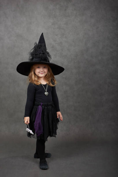 istock Cute girl wearing black witches hat looking at camera 1183834049