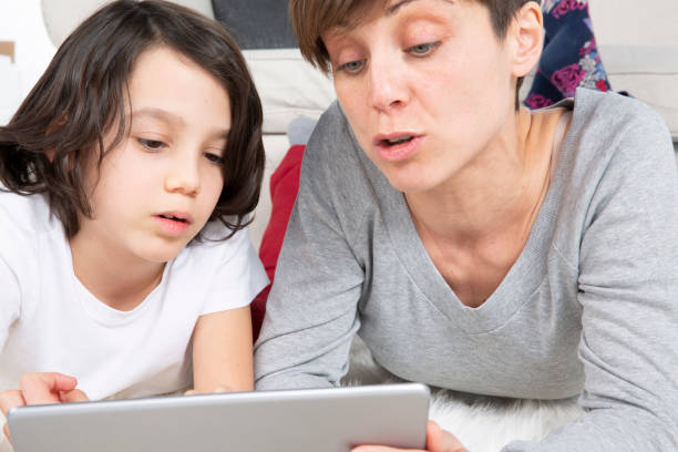 istock Mother and son laying on carpet using digital tablet 1183837304