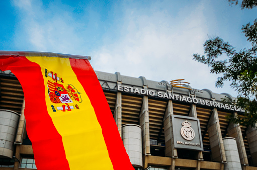 Madrid, Spain - Oct 26, 2019: Santiago Bernabeu Stadium of Real Madrid in Madrid, Spain. Spanish flag on foreground