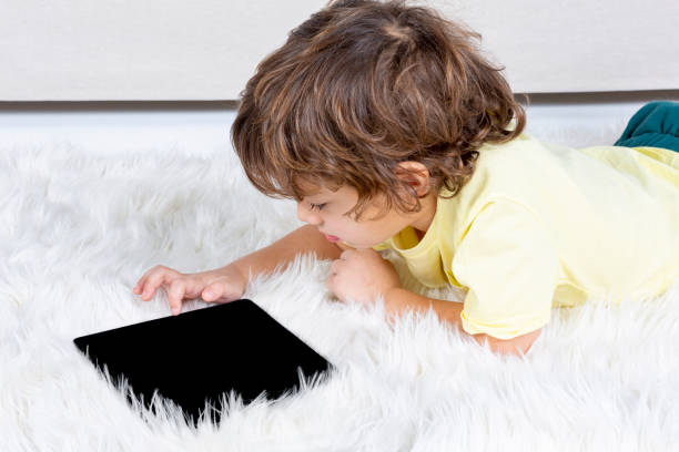 istock Little Boy working tablet on carpet 1183837520